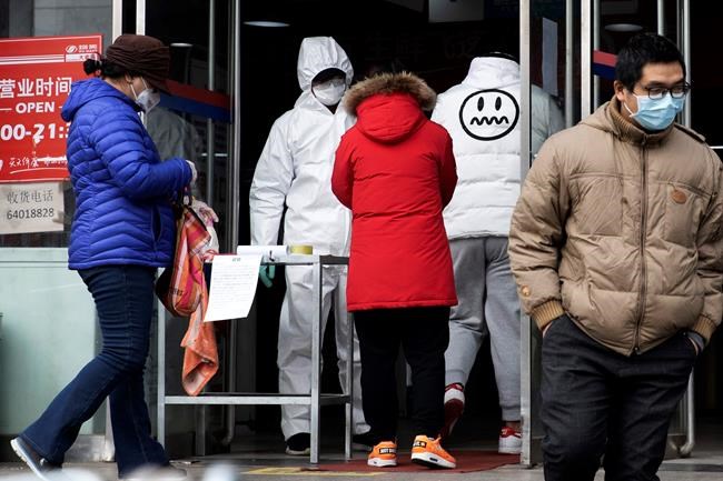 FILE - In this Thursday, Feb. 27, 2020, file photo, a worker in overalls screen for fever at the entrance to a supermarket in Beijing. Health officials reported the first U.S. drug shortage tied to the viral outbreak that is disrupting production in China, but they declined to identify the manufacturer or the product. The Food and Drug Administration said late Thursday, that the drug's maker contacted health officials recently about the shortage, which it blamed on a manufacturing issue with the medicine's key ingredient. (AP Photo/Ng Han Guan, File)