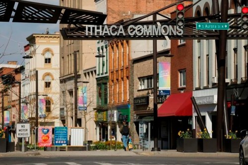 In this April 15, 2020 photo, a lone pedestrian makes their way through the Ithaca Commons in Ithaca, N.Y. Most of the almost 24,000 students at Cornell University and 6,200 more from Ithaca College effectively vanished in March when the pandemic struck, leaving behind struggling restaurants and shops. Locals still reeling from the outbreak and resulting exodus are wondering when - or if - things will get back to normal. (John Munson/Cornell University via AP)