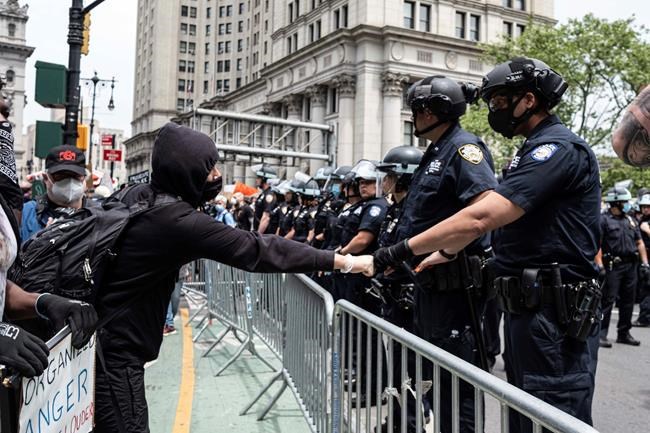 Protesters fist-bump with police officer near Foley Square as part of a demonstration to protest the death of George Floyd, who died May 25 after he was pinned at the neck by a Minneapolis police officer, Tuesday, June 2, 2020, in New York. (AP Photo/Yuki Iwamura)
