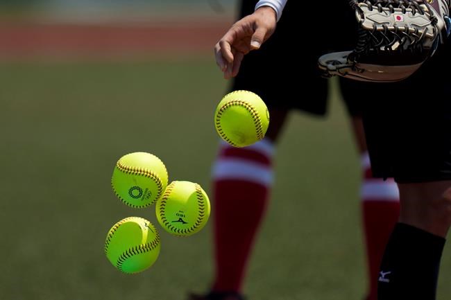 A Japanese softball player tosses the balls into a basket during a training session at the Fukushima Azuma Baseball Stadium ahead of the 2020 Summer Olympics, Tuesday, July 20, 2021, in Fukushima, Japan. (AP Photo/Jae C. Hong)