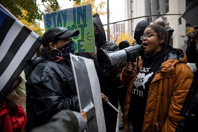 Back the Blue police supporters, left, stand next to Black Lives Matter protesters calling for defunding the police, Thursday, Nov. 5, 2020, in Portland, Ore. (AP Photo/Paula Bronstein)