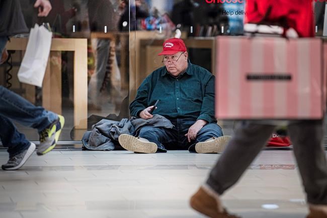 Jefrey Wojtisek sits on the floor as he awaits for the Apple store to open their doors during Black Friday at the King of Prussia Mall in King of Prussia, Pa. Friday, Nov. 28, 2019. (Jose F. Moreno/The Philadelphia Inquirer via AP)
