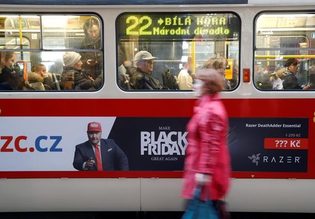 A woman walks past a tram advertising the Black Friday in Prague, Czech Republic, Thursday, Nov. 28, 2019. (AP Photo/Petr David Josek)