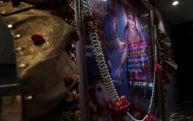 A screen showing news of the market is reflected on a picture of Lakshmi, the Hindu goddess of prosperity at the Bombay Stock Exchange (BSE) office in Mumbai, India, Monday, Nov. 9, 2020. Asian shares rose Monday on relief the U.S. presidential election results were finally decided, with Joe Biden the president-elect. (AP Photo/Rafiq Maqbool)