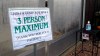 In this Monday, April 27, 2020, photo, with a bottle of hand sanitizer in the background, a sign limits the number of shoppers in the greenhouse of Evergreen Gardens of Vermont in Waterbury Center, Vt. Monday was the the first day businesses such as greenhouses and garden centers could allow a small number of customers inside as part of Vermont's gradual coronavirus pandemic reopening plan. (AP Photo/Wilson Ring)