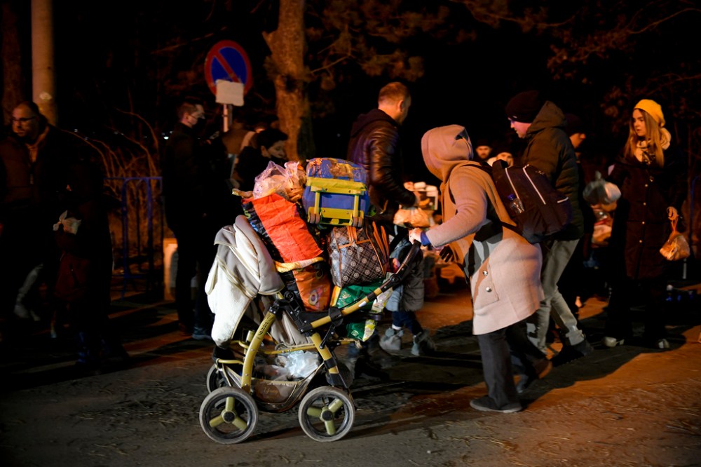 CP
A woman pushes a baby stroller after crossing the border from Ukraine at the Romanian-Ukrainian border, in Siret, Romania which is seeing an influx of refugees from the country as many flee Russia's attacks. (AP Photo/Andreea Alexandru)