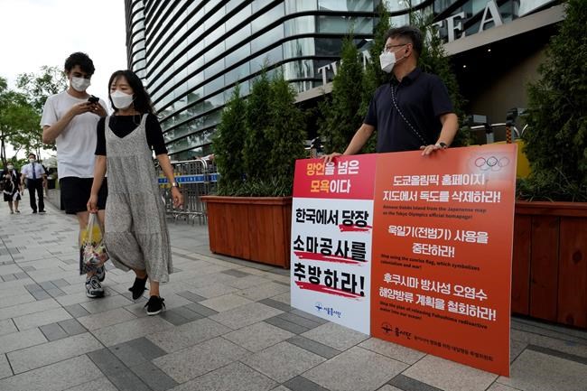 A protester stands to oppose South Korean President Moon Jae-in's possible visit to Japan in front of a building which houses Japanese embassy in Seoul, South Korea, Monday, July 19, 2021. Moon has decided not to visit Japan for the Tokyo Summer Olympics, citing a failure to set up a summit with Japan's prime minister that would produce meaningful results in improving relations. The signs on a banner at left read
