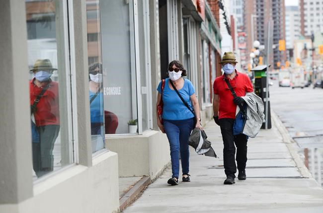 A couple wear masks while out for a walk in downtown Ottawa during the COVID-19 pandemic on Friday, May 1, 2020. THE CANADIAN PRESS/Sean Kilpatrick