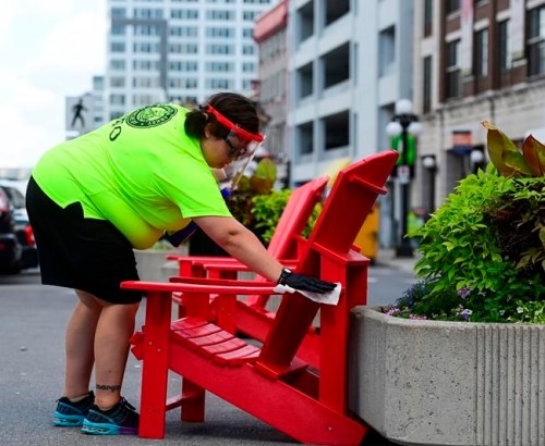 An employee disinfects a public chair in the Byward Market in downtown Ottawa on Monday, Aug. 17, 2020. THE CANADIAN PRESS/Sean Kilpatrick