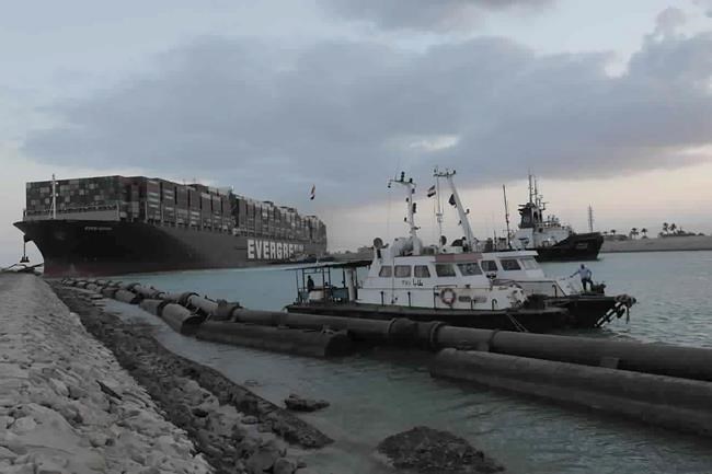 In this photo released by the Suez Canal Authority, tug boats work to free the Panama-flagged, Japanese-owned Ever Given, which is lodged across the Suez Canal, Sunday, March 28, 2021. Two additional tugboats are speeding to canal to aid efforts to free the skyscraper-sized container ship wedged for days across the crucial waterway. That's even as major shippers increasingly divert their boats out of fear the vessel may take even longer to free. (Suez Canal Authority via AP)