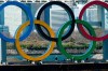 FILE - In this March 24, 2020, file photo, workers stand at the bottom of the Olympic rings at Tokyo's Odaiba district. Just two months after the unprecedented postponement. Chief Executive Toshiro Muto was asked Thursday, May 28, 2020 about progress rescheduling next year's Tokyo Olympics. (AP Photo/Eugene Hoshiko, File)
