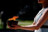 FILE - In this March 12, 2020, file photo, an actress, playing the role of the priestess, holds the flame during the flame lighting ceremony at the closed Ancient Olympia site, birthplace of the ancient Olympics in southern Greece. The Olympic flame from Greece is set to arrive in Japan even as the opening of the the Tokyo Games in four months is in doubt with more voices suggesting the games should to be postponed or canceled because of the worldwide virus pandemic. (AP Photo/Thanassis Stavrakis, File)