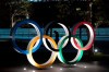 FILE - In this March 24, 2020, file photo, a man is seen through the Olympic rings in front of the New National Stadium in Tokyo. Tokyo Olympic organizers on Friday, Nov. 27, 2020 announced a series of 18 test events set to begin in March and run into May. (AP Photo/Jae C. Hong, File)