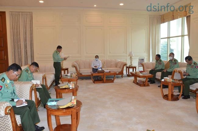 In this photo released by The Military True News Information Team, Myanmar Acting President Myint Swe, center, military chief Senior Gen. Min Aung Hlaing, standing at left, and other military members of National Defence and Security Council attend a meeting at Presidential Palace in Naypyitaw, Myanmar Monday, Feb. 1, 2021. (The Military True News Information Team via AP)