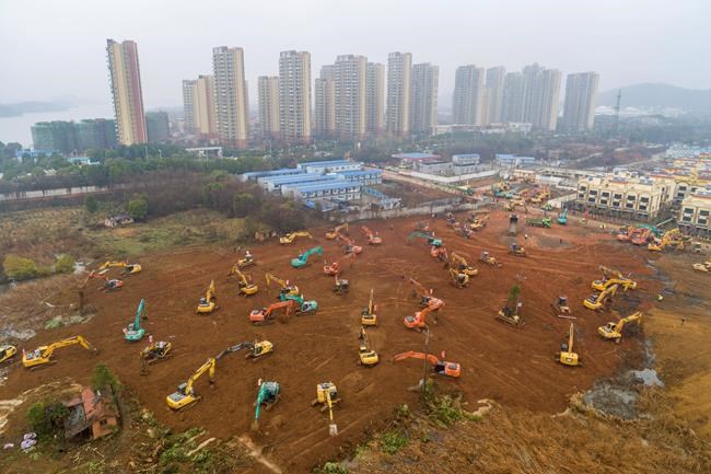 FILE - In this Friday, Jan. 24, 2020, file photo, heavy equipment works at a construction site for a field hospital in Wuhan in central China's Hubei Province. A patient in Southern California is third person in the U.S. to be diagnosed with the new pneumonia-like virus from China, health officials said. (Chinatopix via AP, File)