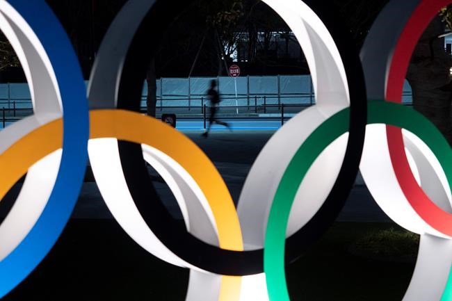 FILE - In this March 30, 2020, file photo, a man jogs past the Olympic rings in Tokyo. Almost two months after the Tokyo Olympics were postponed until next year, CEO Toshiro Muto on Friday, May 15, 2020, said he still could not give an estimate of how much the delay will cost. (AP Photo/Jae C. Hong, File)