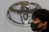 FILE - In this Nov. 2, 2020, file photo, visitor wearing a face mask to help curb the spread of the coronavirus walks by the logo of Toyota Motor Corp. at its showroom in Tokyo. Toyota won't be airing any Olympic-themed advertisements on Japanese TV during the Tokyo Games despite being one of the IOC's top corporate sponsors. The unusual decision by the country's top automaker underlines how polarizing the Games have become in Japan as COVID-19 infections rise ahead of the July 23, 2021, opening ceremony.(AP Photo/Koji Sasahara, File)