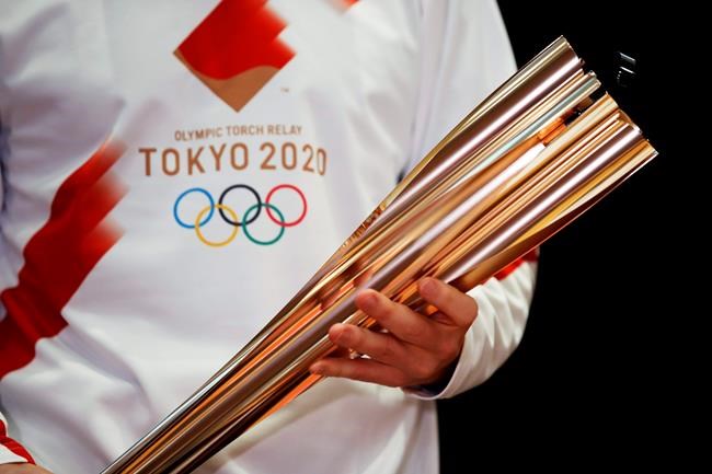 FILE - In this Feb. 24, 2020, file photo, Greek singer Sakis Rouvas wears the uniform of the torch relay runners in Athens, Greece, as he holds the torch of the 2020 Tokyo Olympic Games during a presentation of the torch relay within in Greece. Organizers have talked in detail about plans for the start of next week's Tokyo Olympic torch relay. The message is simple: exercise extreme caution. The start of the relay on March 25 from northeastern Fukushima prefecture kicks off four months of crisscrossing Japan with the torch. The relay will involve 10,000 runners and the chance of spreading COVID-19 across the country is a real threat.(AP Photo/Thanassis Stavrakis, File)