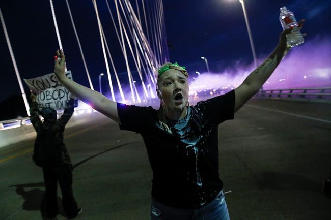 In this Monday, June 1, 2020, photo, a protester raises her arms on the Margaret Hunt Hill Bridge while demonstrating against police brutality in Dallas. Protests continue over the death of George Floyd, a black man who died after being restrained by Minneapolis police officers on May 25. (Ryan Michalesko/The Dallas Morning News via AP)