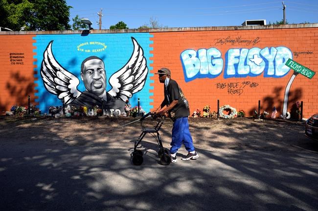 Ronaly Brooks walks past a mural in the neighborhood where George Floyd grew up Tuesday, April 20, 2021, in Houston. Former Minneapolis police Officer Derek Chauvin has been convicted of murder and manslaughter in the death of George Floyd, the explosive case that triggered worldwide protests, violence and a furious reexamination of racism and policing in the U.S. (AP Photo/David J. Phillip)