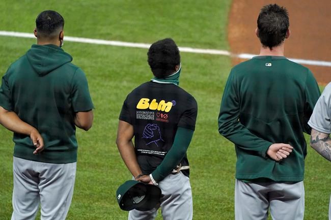 Oakland Athletics' Tony Kemp wears a Black Lives Matter shirt as he stands with his team during the playing of the national anthem before a baseball game against the Texas Rangers in Arlington, Texas, Wednesday Aug. 26, 2020. (AP Photo/Tony Gutierrez)
