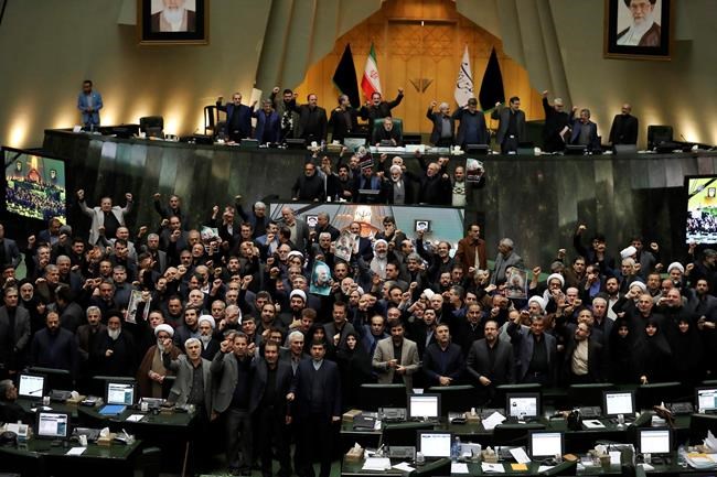 Iranian lawmakers chant slogans as some of them hold posters of Gen. Qassem Soleimani, who was killed in Iraq in a U.S. drone attack, in an open session of parliament, in Tehran, Iran, Tuesday, Jan. 7, 2020. Iran's parliament has passed an urgent bill declaring the U.S. military's command at the Pentagon in Washington and those acting on its behalf