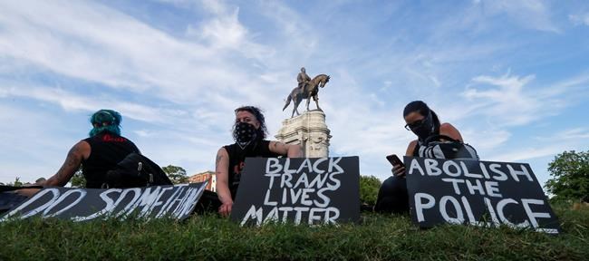 Protesters hold signs around the statue of Confederate Gen. Robert E. Lee on Monument Avenue on Tuesday, June 2, 2020, in Richmond, Va. The crowd protesting police brutality chanted