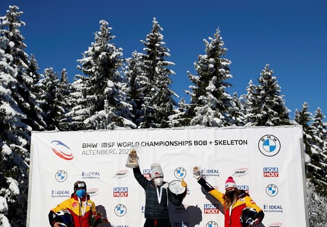 Bobsleigh pilot Kaillie Humphries of the United States, center, celebrates on the podium after taking first place in the women's monobob race at the Bobsleigh and Skeleton World Championships in Altenberg, Germany, Sunday, Feb.14, 2021. At left is second place Germany's Stephanie Schneider and at right is third place Germany's Laura Nolte. (AP Photo/Matthias Schrader)