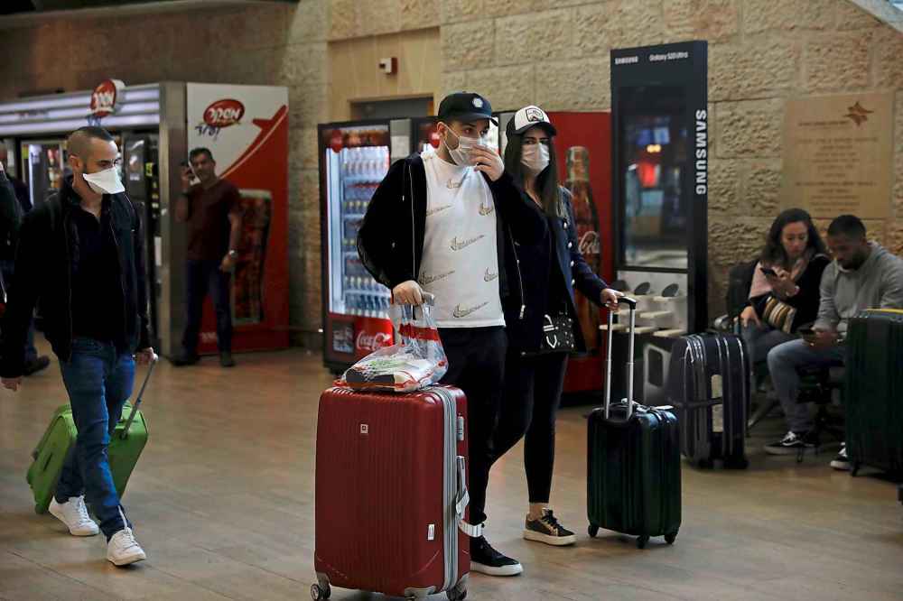 Passengers wearing protective masks arrive in Ben Gurion Airport near Tel Aviv, Israel on Thursday. (Ariel Schalit / The Associated Press)