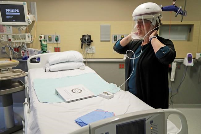 In this Thursday, Jan. 23, 2020 photo, Robin Addison, a nurse at Providence Regional Medical Center in Everett, Wash., demonstrates how she wears a respirator helmet with a face shield. It is similar to the one she used when she helped treat a man, currently in isolation at the hospital, who is believed to be the first person in the U.S. to have contacted a dangerous new virus that originated in China. (AP Photo/Ted S. Warren)