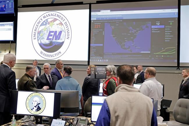 A map showing the spread of the COVID-19 coronavirus in the United States is displayed as Vice President Mike Pence, at lower left, tours the Washington State Emergency Operations Center, Thursday, March 5, 2020 at Camp Murray in Washington state. (AP Photo/Ted S. Warren)