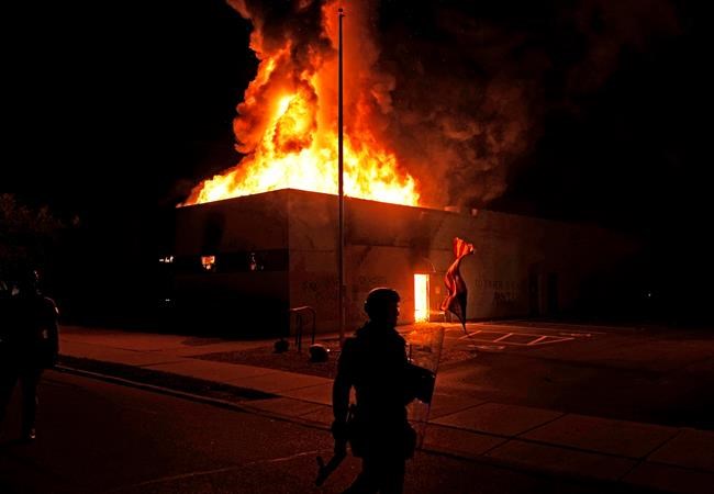 An American flag falls from its pole as police attempt to secure the area after protesters set fire to the department of corrections building, late Monday, Aug. 24, 2020, in Kenosha, Wis. Protests have erupted following the police shooting of Jacob Blake a day earlier. (AP Photo/David Goldman)