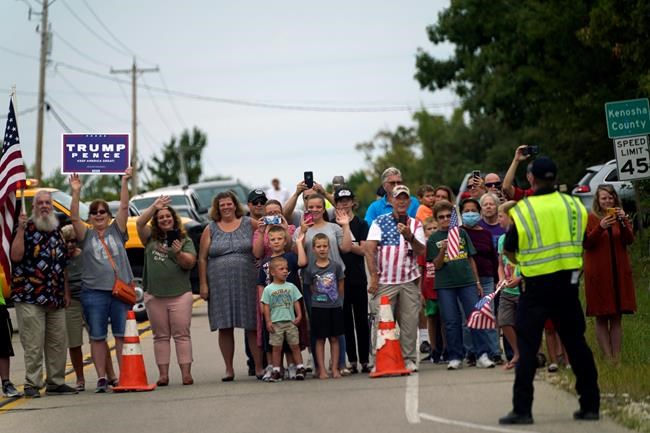 People line up to watch as the motorcade with President Donald Trump passes by Tuesday, Sept. 1, 2020, in Kenosha, Wis. (AP Photo/Evan Vucci)