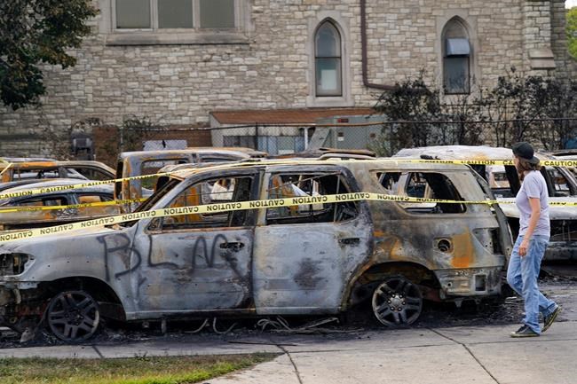 A pedestrian walks past some burned out cars after earlier protests Tuesday, Aug. 25, 2020, in Kenosha, Wis. Anger over the shooting of Jacob Blake, a Black man, by police spilled into the streets of Kenosha for a second night Monday. (AP Photo/Morry Gash)