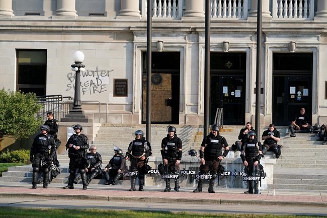 Police in riot gear stand outside the Kenosha County Court House Monday, Aug. 24, 2020, in Kenosha, Wis. Kenosha police shot a man Sunday evening, setting off unrest in the city after a video appeared to show the officer firing several shots at close range into the man's back. (AP Photo/Morry Gash)