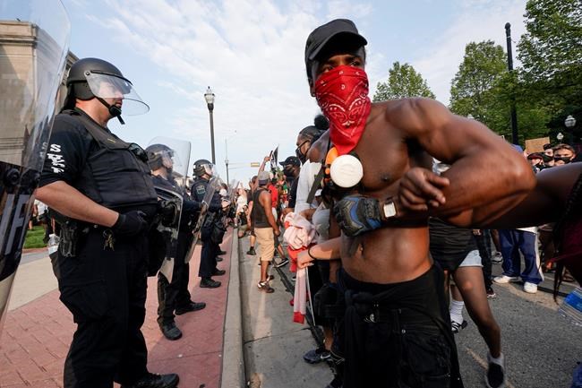 Protesters link arms in front of a police line outside the Kenosha County courthouse Monday, Aug. 24, 2020, in Kenosha, Wis. Wisconsin Gov. Tony Evers has summoned the National Guard to head off another round of violent protests after the police shooting of a Black man turned Kenosha into the nation's latest flashpoint city in a summer of racial unrest. (AP Photo/Morry Gash)