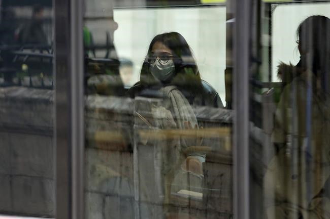 A woman wears a protective mask as she travels onboard a London bus near the Bank of England in London, Wednesday, March 11, 2020. Britain's Chancellor of the Exchequer Rishi Sunak will announce the first budget since Britain left the European Union. (AP Photo/Matt Dunham)