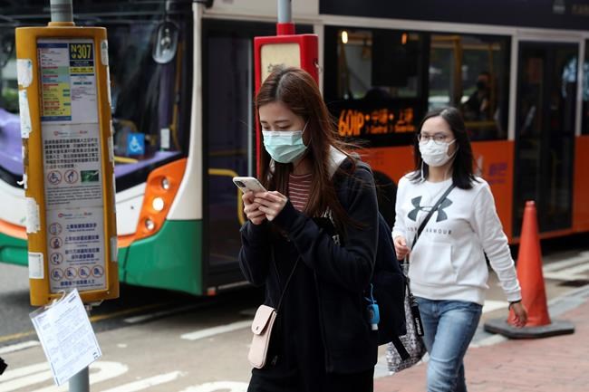 People wear protective face masks on a street in Hong Kong, Friday, Jan 24, 2020. China closed off a city of more than 11 million people Thursday, halting transportation and warning against public gatherings, to try to stop the spread of a deadly new virus that has sickened hundreds and spread to other cities and countries in the Lunar New Year travel rush. (AP Photo/Achmad Ibrahim)