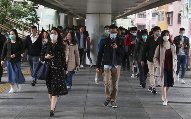 People wear protective face masks on a bridge in Hong Kong, Friday, Jan 24, 2020. China closed off a city of more than 11 million people Thursday, halting transportation and warning against public gatherings, to try to stop the spread of a deadly new virus that has sickened hundreds and spread to other cities and countries in the Lunar New Year travel rush. (AP Photo/Achmad Ibrahim)