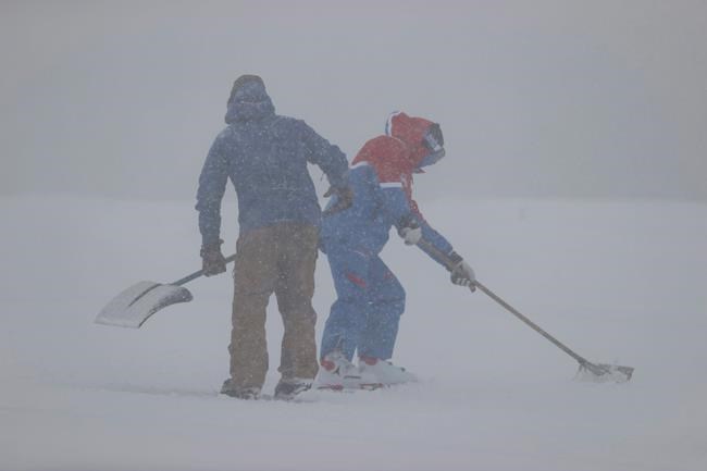Ski-men work the course as the fog forced to interrupt an alpine ski, men's World Cup downhill, in Saalbach-Hinterglemm, Austria, Friday, March 5, 2021. (AP Photo/Alessandro Trovati)
