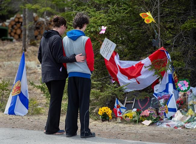 Visitors to a roadside memorial pays their respects in Portapique, N.S. on Friday, April 24, 2020. RCMP say at least 22 people are dead after a man who at one point wore a police uniform and drove a mock-up cruiser, went on a murderous rampage in Portapique and several other Nova Scotia communities. THE CANADIAN PRESS/Andrew Vaughan