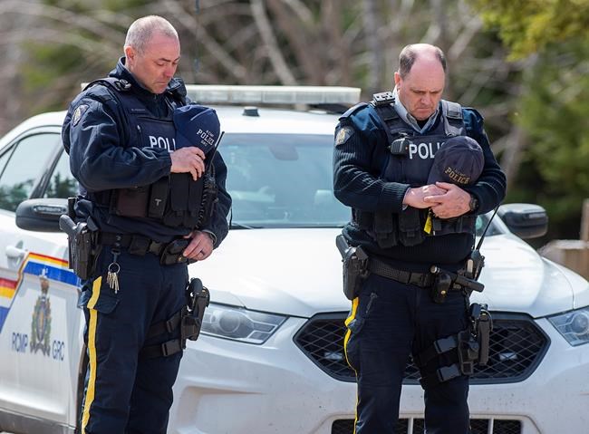 Two RCMP officers observe a moment of silence to honour slain Const. Heidi Stevenson and the other 21 victims of the mass killings at a checkpoint on Portapique Road in Portapique, N.S. on Friday, April 24, 2020. At least 22 people are dead after a man, who at one point wore a police uniform and drove a mock-up cruiser, went on a murder rampage in Portapique and several other Nova Scotia communities. THE CANADIAN PRESS/Andrew Vaughan