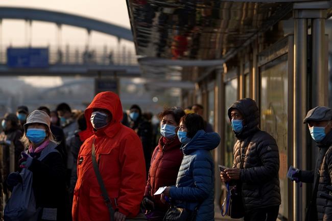 Commuters wearing face masks to help curb the spread of the coronavirus line-up to board a bus at a bus stand in Beijing, Sunday, Dec. 6, 2020. Provincial governments across China are placing orders for experimental, domestically made coronavirus vaccines, though health officials have yet to say how well they work or how they may reach the country's 1.4 billion people. (AP Photo/Andy Wong)