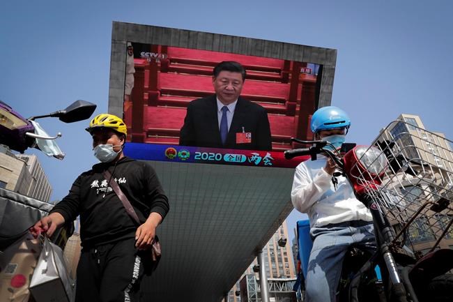 Food delivery workers wearing face masks to protect against the spread of the new coronavirus prepare to delivery foods near a TV screen showing Chinese President Xi Jinping attending the closing ceremony of the National People's Congress in a news report, in Beijing, China, Thursday, May 28, 2020. China's ceremonial legislature on Thursday endorsed a national security law for Hong Kong that has strained relations with the United States and Britain. (AP Photo/Andy Wong)