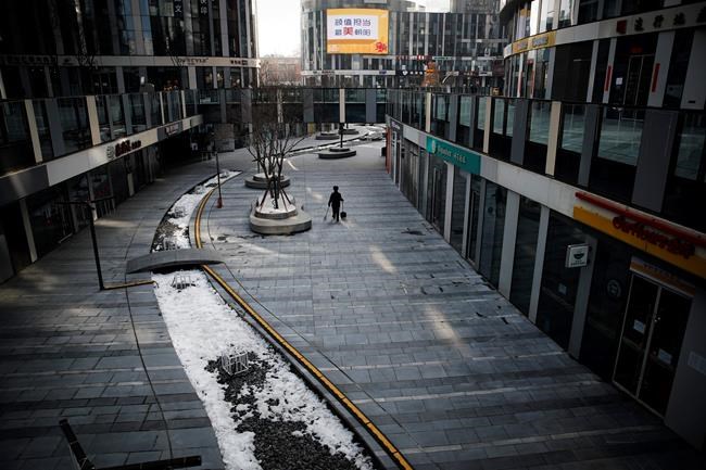 A cleaner walks through a deserted compound of a commercial office building in Beijing, Monday, Feb. 10, 2020. China reported a rise in new virus cases on Monday, possibly denting optimism that its disease control measures like isolating major cities might be working, while Japan reported dozens of new cases aboard a quarantined cruise ship. (AP Photo/Andy Wong)
