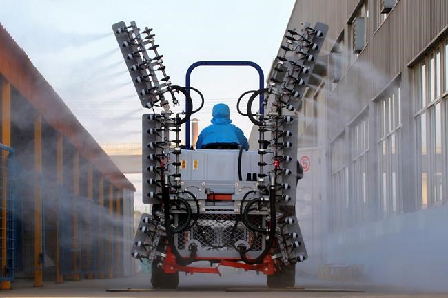 A worker in a tractor operates electrostatic spraying to disinfect the workplace following the coronavirus outbreak, in Yantai city in east China's Shandong province, Sunday, Feb. 9, 2020. China's virus death toll rose above 800, passing the number of fatalities in the 2002-2003 SARS epidemic, but fewer new cases were reported in a possible sign its spread may be slowing as other nations step up efforts to block the disease. (Chinatopix via AP)