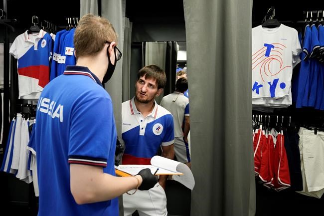 Russian athlete Musa Mogushkov, center, tries on the new Olympic gear for Russian athletes for the Tokyo Games by the brand ZASPORT in Moscow, Russia, Thursday, July 1, 2021. (AP Photo/Alexander Zemlianichenko)