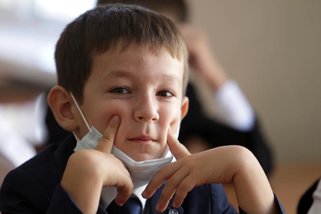 A boy wearing a face mask to protect against coronavirus sits in a classroom during a ceremony marking the start of classes at a school as part of the traditional opening of the school year known as