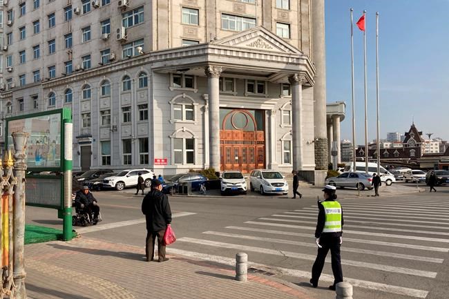 A police officer stands outside a court building in Dandong in northeastern China's Liaoning Province, Friday, March 19, 2021. China was expected to open the first trial Friday for Michael Spavor, one of two Canadians who have been held for more than two years in apparent retaliation for Canada's arrest of a senior Chinese telecom executive. (AP Photo/Ken Moritsugu)