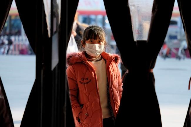 A girl wearing a face mask stands in the entrance to a shop in Wuhan in central China's Hubei Province, Friday, Jan. 31, 2020. The U.S. advised against all travel to China as the number of cases of a worrying new virus spiked more than tenfold in a week, including the highest death toll in a 24-hour period reported Friday. (AP Photo/Arek Rataj)